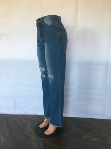 Detail of blue high-waisted flare jeans featuring distressed knees and frayed hems