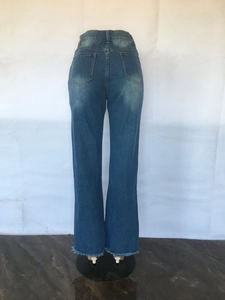 Detail of frayed raw hem and classic back pockets on dark blue flared denim jeans