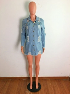 Detail of light blue denim shirt dress with distressed frayed hem and gold buttons