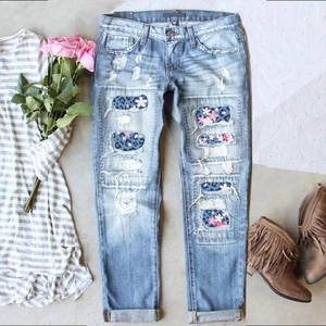 Light blue ripped jeans with floral leopard print patches on light grey background