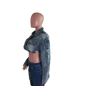 Détail d'une veste courte en jean avec ourlets effilochés et délavage dégradé tendance