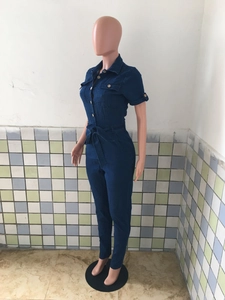 Detail view of dark blue denim jumpsuit with short sleeves, lapels, and waist tie belt