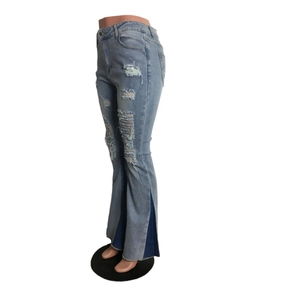 Detail of high waist flared jeans with distressed knee holes and blue patchwork hem