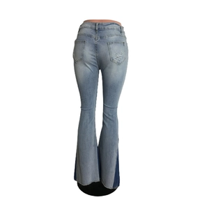 Detail view of high waist flared jeans featuring distressed pocket and raw hem finishes