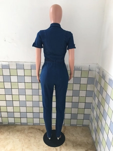 Back view of a short sleeve dark blue denim jumpsuit with waist tie and rear pockets