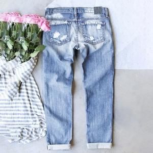 Flat lay of distressed blue straight leg jeans with ripped back pockets and cuffed hems