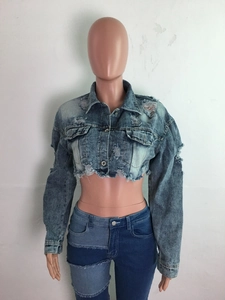 Détail de la veste en jean courte avec bords effilochés et effet de lavage dégradé