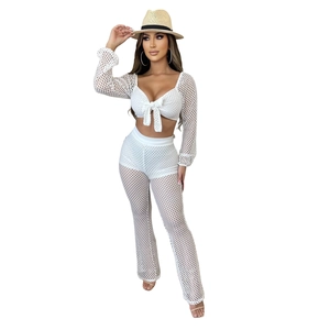 Detail of white crochet mesh two-piece set featuring long-sleeve crop top and flare pants