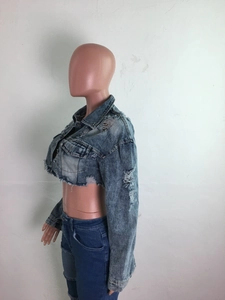 Détail de la veste courte en jean avec finitions vieillies et bords effilochés
