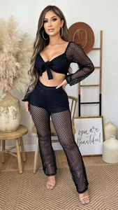 Detail of black mesh two-piece set featuring sheer long sleeve top and flared trousers