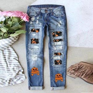 Detail of Halloween pumpkin print and distressed ripped patches on blue denim jeans