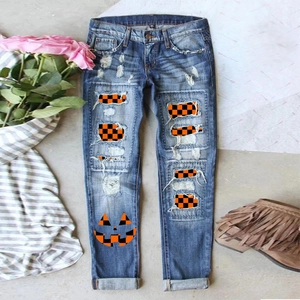 Detailed macro view of distressed blue jeans with orange plaid patches and pumpkin print