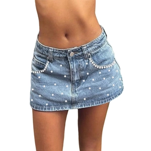 Detail of high-waist denim mini skirt with pearl embellishments and frayed hem edge