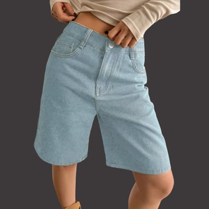 Detail view of high waist light blue denim Bermuda shorts with classic metal button closure