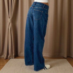 Detail view of deep blue high-waisted wide-leg denim jeans with back pocket and twill texture