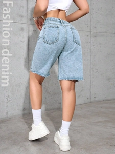 Detail of high waisted light blue denim shorts with distressed raw hem and back pockets