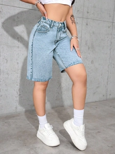 Detail of light blue high-waisted denim shorts featuring raw hems and snow wash texture