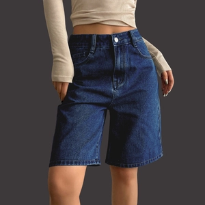 Detailed close-up of dark blue high-waisted denim Bermuda shorts with faded whiskers