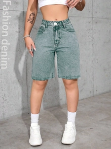 Detail of acid wash denim texture on high-waisted shorts with a raw hem and metal button