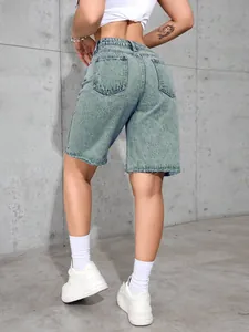 Detail showing high-waisted denim shorts with raw hem, dual back pockets and washed finish