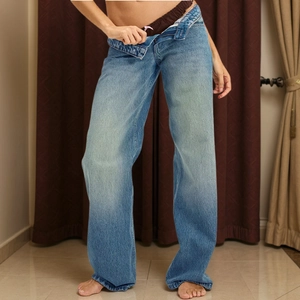 Detail of high-waist wide-leg light blue denim jeans showing button and zipper texture