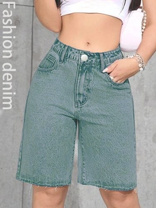Detail of high-waisted denim shorts featuring frayed hems in a washed blue-green tone