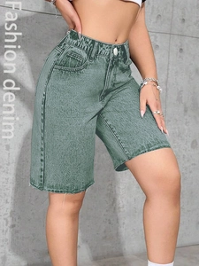 Close-up of high-waisted denim shorts with elastic waist and raw hem in grey-green finish