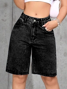 Detail of high-waisted black washed denim bermuda shorts featuring raw fringe hems
