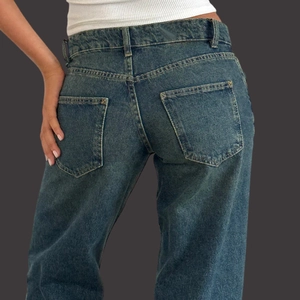 Detailed back view of high waist dark blue denim jeans showing pockets and stitching