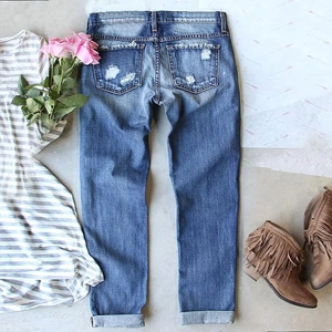Flat lay of distressed blue straight leg jeans with ripped details and casual outfit styling