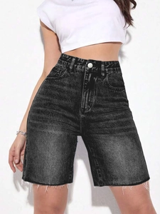Detailed view of high waisted black denim shorts with raw hem and distressed texture on model