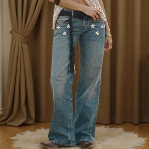 Detail of high-waist flare jeans featuring colorful sequin flower appliques and a black belt
