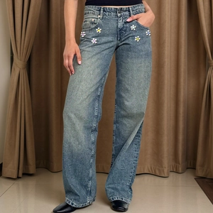 Detailed view of colorful flower patches on high waist light blue wide-leg denim jeans
