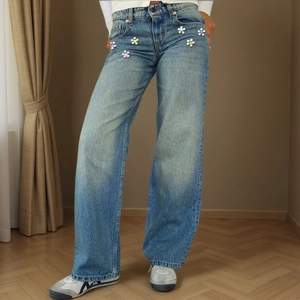 Detail of vintage blue wide leg jeans featuring colorful beaded 3D flower embellishments