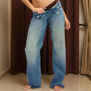 Detailed view of light blue straight-leg jeans with unique colorful flower button accents