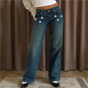 Detailed view of dark blue washed denim jeans featuring sparkling rhinestone flower accents