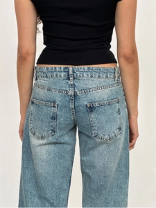 Detail of light blue washed denim pants featuring high-waist back pockets and stitching