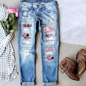 Distressed blue wash denim jeans with pink glitter heart patches and plaid detailing