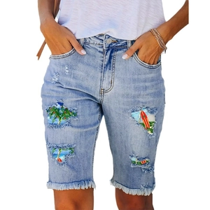 Women's light blue distressed denim shorts with tropical beach print lining detail