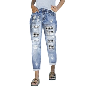 Close-up of blue ripped jeans with black white plaid patches and dandelion embroidery