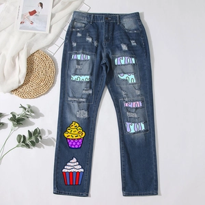 Distressed straight-leg blue denim jeans with colorful cartoon cupcake prints and patches