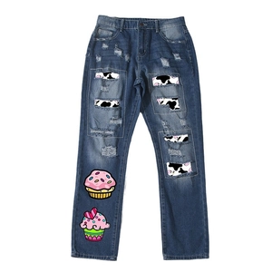 Relaxed straight leg blue distressed jeans featuring cow print patches and cupcake embroidery