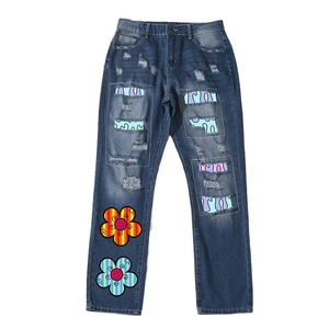 Distressed straight-leg dark blue jeans featuring colorful floral patches and ripped details