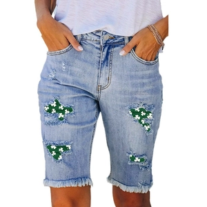 Women's light blue distressed denim shorts with St. Patrick's clover patches and raw hems