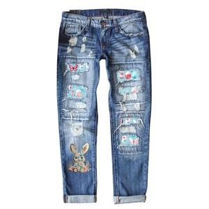 Women's straight-leg blue ripped jeans featuring floral and rabbit print patches