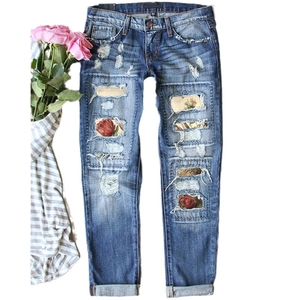 Distressed dark blue washed jeans with floral patch inserts and cuffed hems