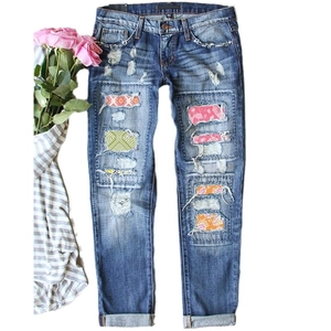 Women's straight leg blue washed denim jeans with distressed holes and floral patches