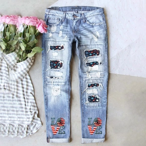 Détail d'un jean bleu clair déchiré avec écussons drapeau US et imprimé LOVE