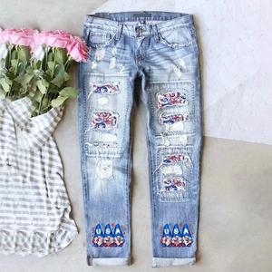 Détail d'un jean déchiré avec motifs de gnomes USA et patchs en tissu tricolore