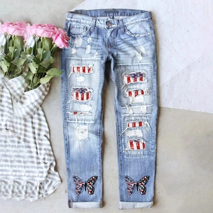 Détail de jean déchiré avec patchs drapeau américain et imprimé papillon en denim clair